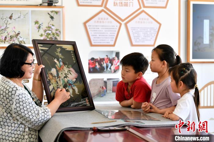 圖為裴小苓正在向孩子們介紹玻璃油畫歷史及工藝技巧。　高丹鈺 攝