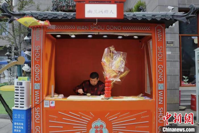 龔保新身著傳統(tǒng)服飾坐在自己的糖畫攤前進(jìn)行創(chuàng)作?！⒂駶?攝
