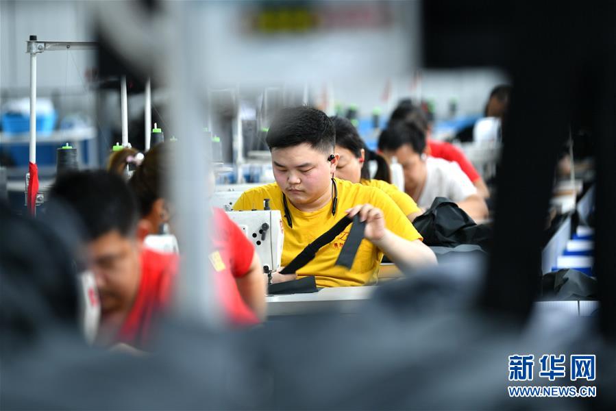 6月16日，在湖北省宣恩縣高羅鎮(zhèn)一間扶貧工廠(chǎng)的車(chē)間里，就業(yè)農(nóng)民在制衣生產(chǎn)線(xiàn)上工作?！　∽?月下旬以來(lái)，湖北省恩施土家族苗族自治州宣恩縣通過(guò)優(yōu)先復(fù)工復(fù)產(chǎn)、部門(mén)跟蹤服務(wù)、暢通銷(xiāo)售渠道等措施，確保當(dāng)?shù)?7家建在易地扶貧搬遷安置點(diǎn)的扶貧工廠(chǎng)、車(chē)間正常有序生產(chǎn)銷(xiāo)售，為農(nóng)村低收入群體就業(yè)提供保障。 新華社發(fā)（宋文 攝）