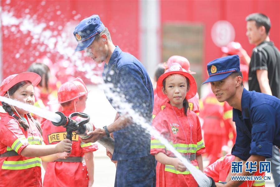 8月6日，消防員在畢節(jié)市消防救援支隊碧陽大道特勤站帶領(lǐng)學(xué)生體驗消防水槍。 新華社發(fā)（陳曦 攝）