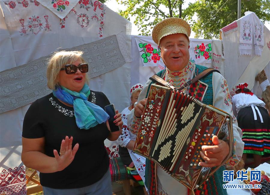 9月26日，在白俄羅斯首都明斯克郊區(qū)，一名女士與一名身著民族服裝的樂(lè)手合影。 隨著當(dāng)?shù)厍锸盏幕窘Y(jié)束，白俄羅斯各地相繼舉辦農(nóng)業(yè)展銷(xiāo)節(jié)等活動(dòng)，歡慶秋收。 新華社發(fā)（任科夫攝）