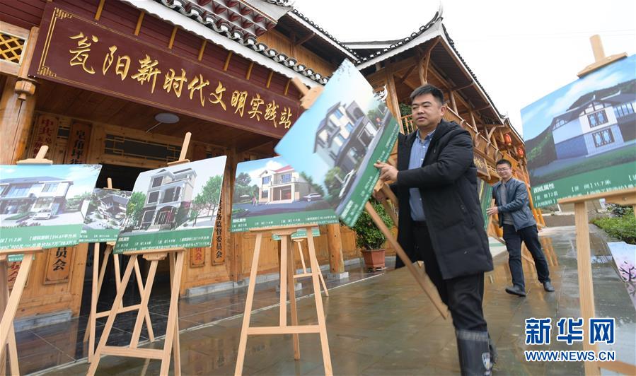 10月20日，在貴州省銅仁市玉屏侗族自治縣皂角坪街道甕陽(yáng)村，村民夏政華（前）和幫扶干部一起擺放農(nóng)村規(guī)范建房的設(shè)計(jì)效果圖，供村民選擇。 新華社記者楊楹攝