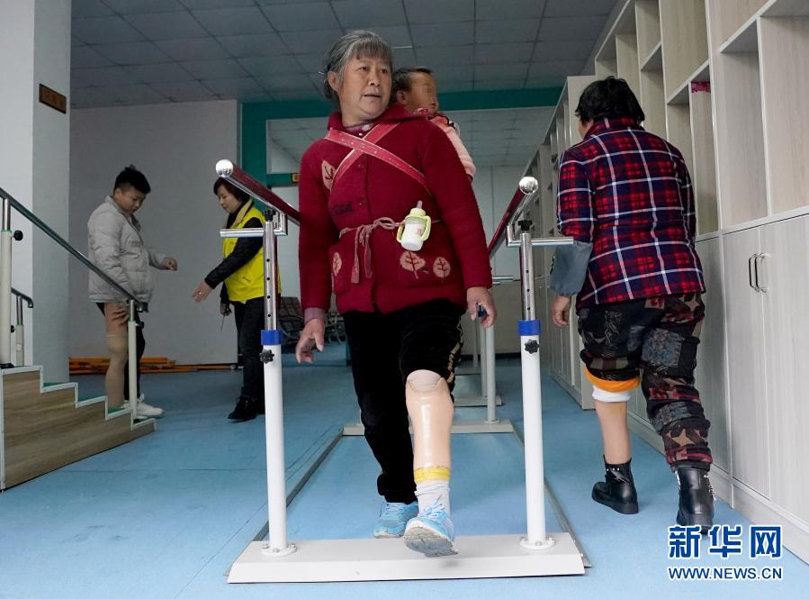 11月25日，來自織金縣中寨鎮(zhèn)水頭村的張胡敏老人背著孫子在康復(fù)中心進(jìn)行訓(xùn)練。貴州省畢節(jié)市織金縣積極推廣中央專項(xiàng)彩票公益金助殘項(xiàng)目，自2013年以來，開展為全縣殘疾人免費(fèi)安裝假肢活動(dòng)，并負(fù)責(zé)其康復(fù)訓(xùn)練，目前已有近300人受益。新華社記者 王毓國(guó) 攝