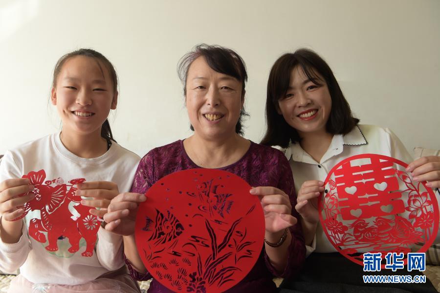 　　2月21日，在烏海市海南區(qū)新橋花園，李華（中）與外孫女高宇晨（左）、大女兒譚紅葉一起展示剪紙作品。新華社記者 李志鵬 攝